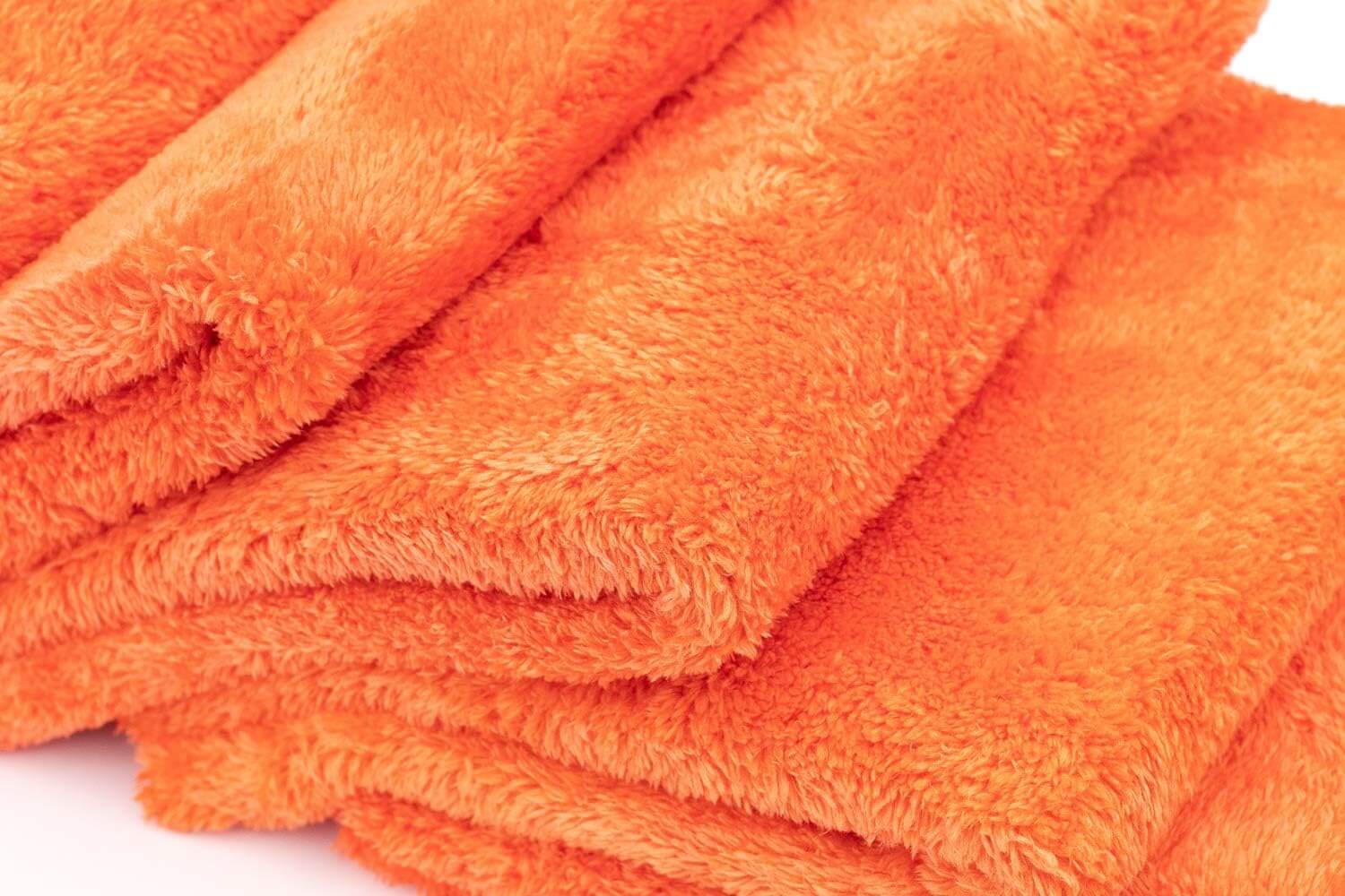 Close-up of stacked orange Herbionyx UltraSoft Microfiber Towels, ideal for polishing and detailing surfaces.